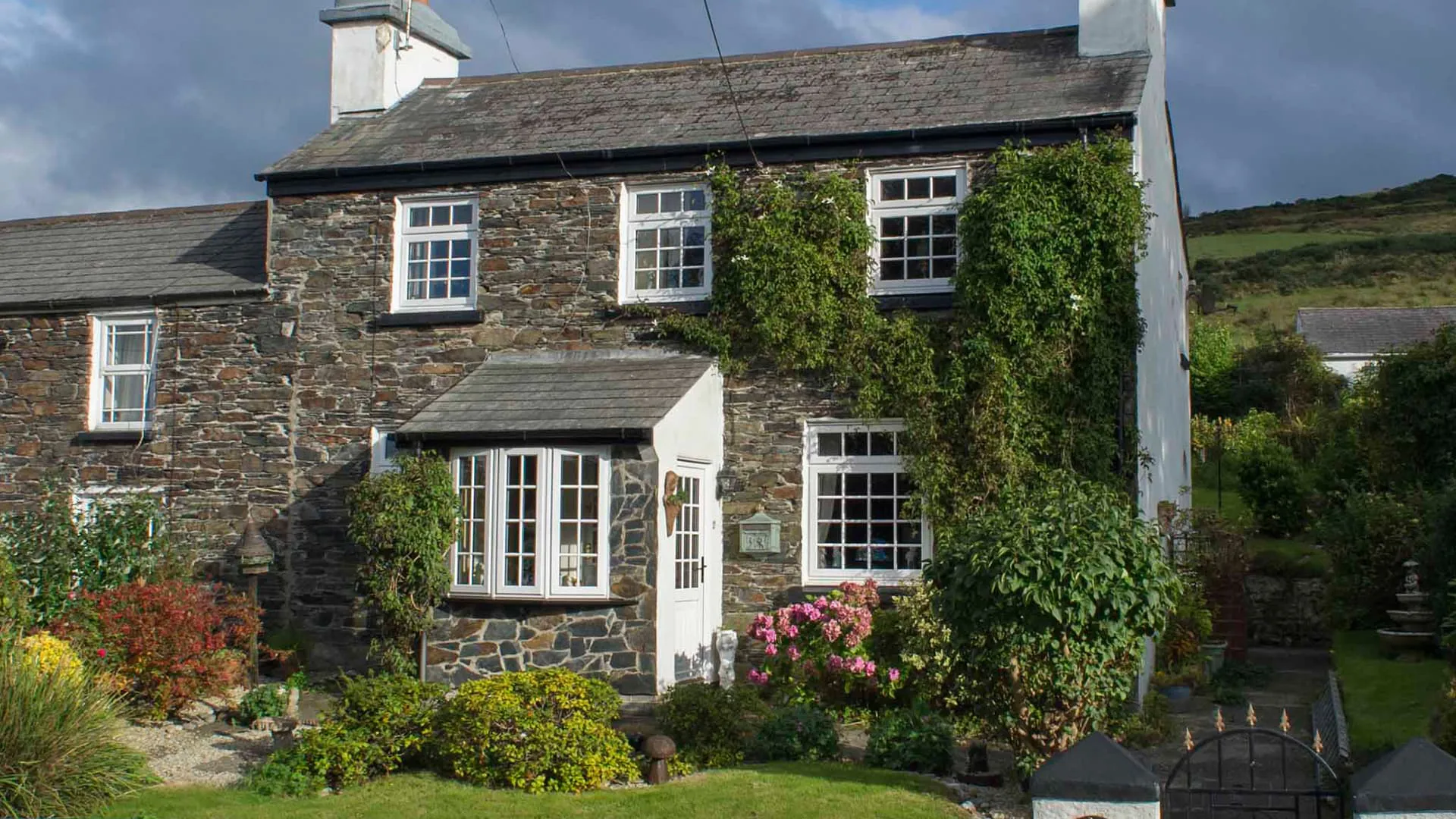Stone house with white windows and gardens