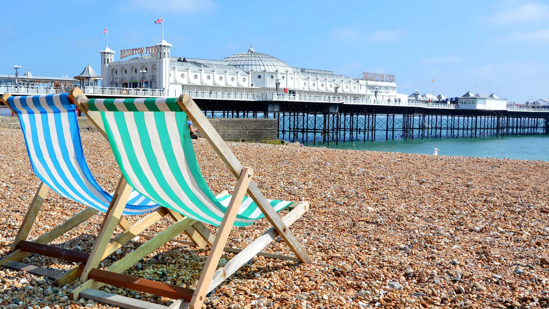Striped beach chairs on pebble beach near pier