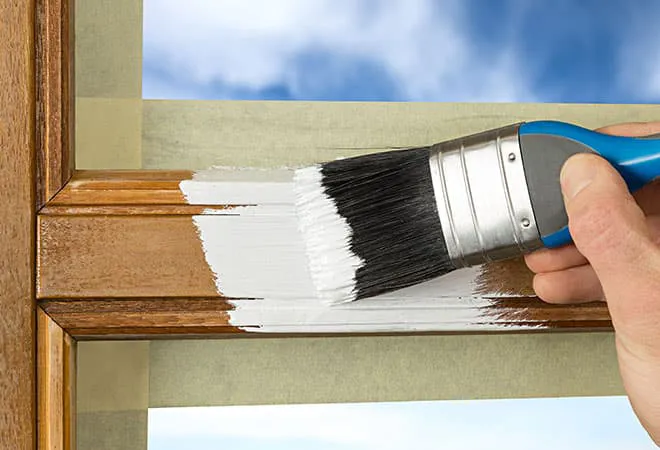 Painting wooden window frame white with a paintbrush