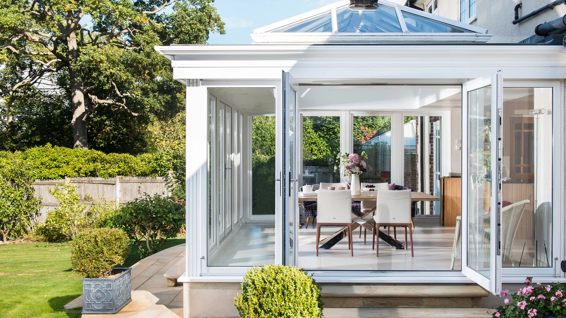 Everest conservatory with white frame and glass doors open to garden and dining area