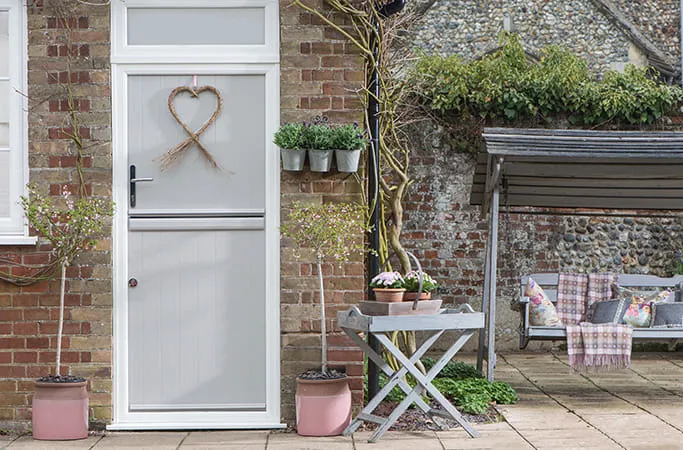 Light gray door with heart wreath and pink planters