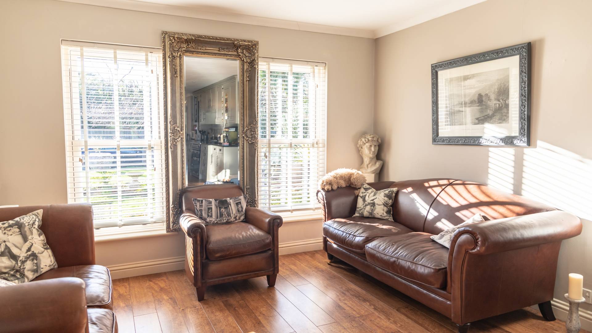 Brown leather armchairs and sofa in a living room with white blinds
