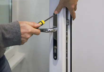 Person fixing a white door handle with a screwdriver