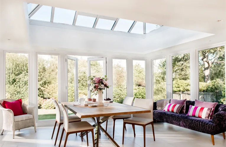 White Everest conservatory with large windows and wooden table