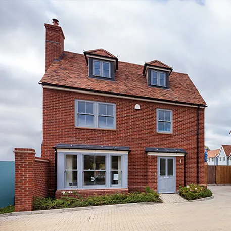 Red brick house with grey windows and tiled roof
